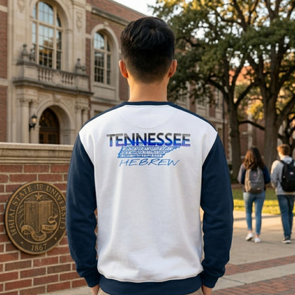 Back view of a man in a white and navy sweatshirt with a "TENNESSEE HEBREW" graphic, standing on a university campus near a brick wall.