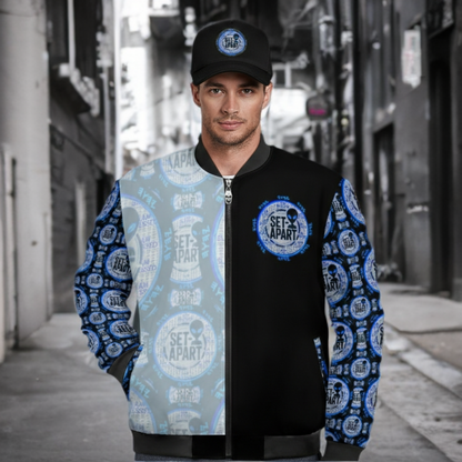 A man in an urban alley wearing a black and blue "Set-Apart" bomber jacket with alien motifs and a matching baseball cap.