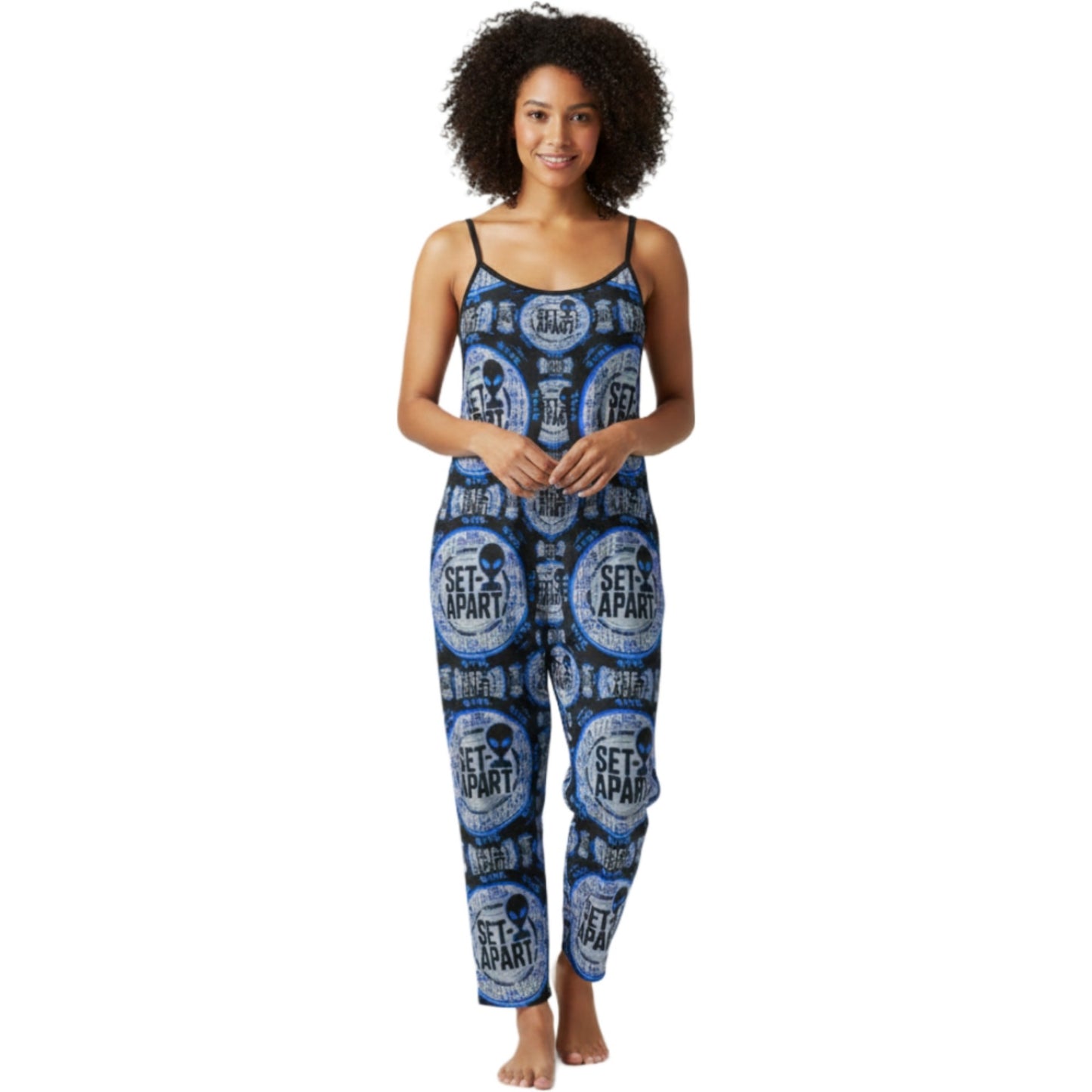 Front view of a person wearing a blue and black patterned sleeveless jumpsuit with spaghetti straps featuring circular "SET APART" alien head graphics.