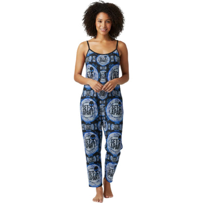 Front view of a person wearing a blue and black patterned sleeveless jumpsuit with spaghetti straps featuring circular "SET APART" alien head graphics.
