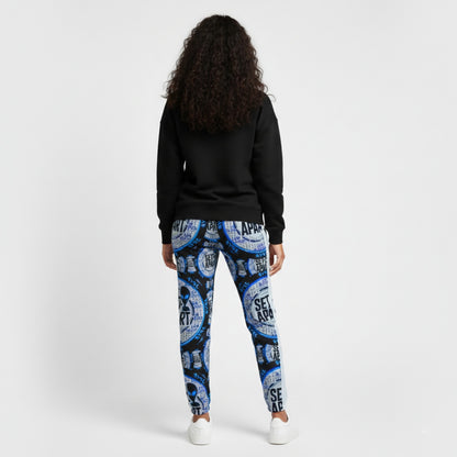 A woman in a black hoodie and blue graphic joggers with white sneakers. She is shown in back view against a white background.