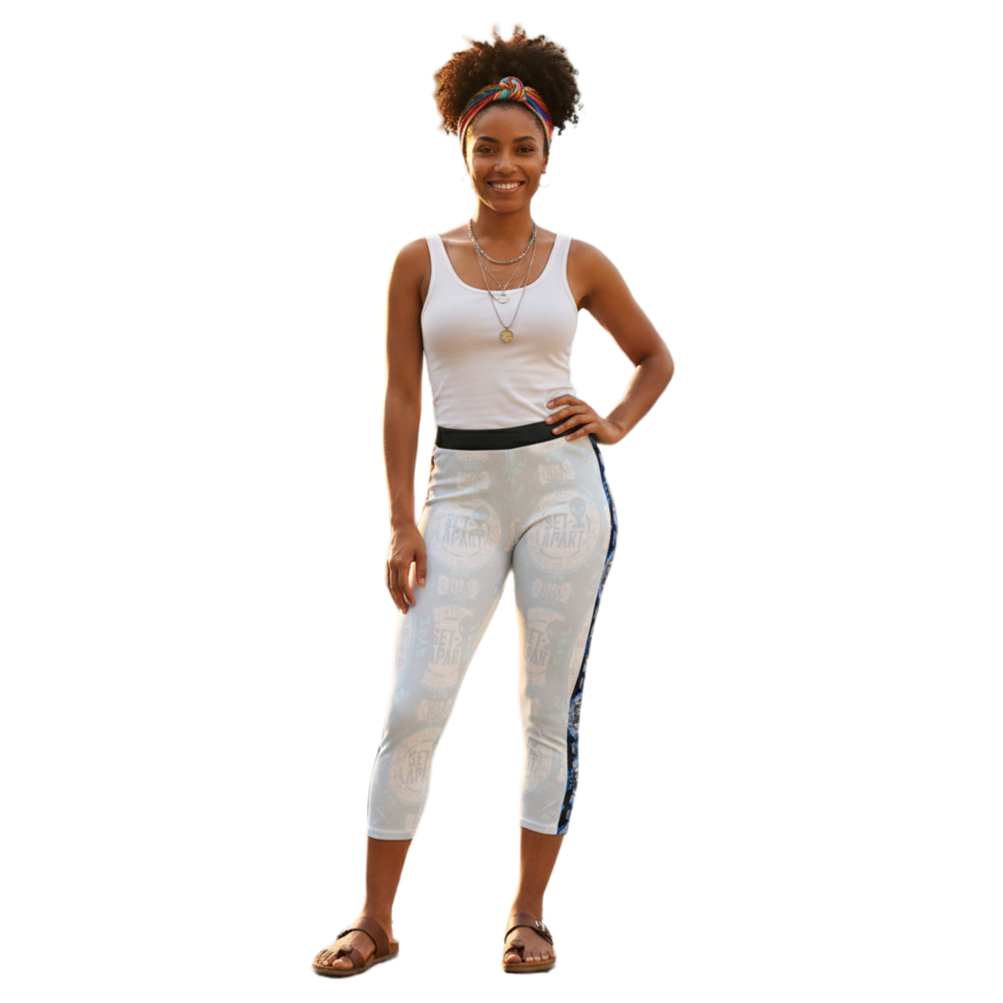 A woman in a white tank and patterned leggings with a blue side stripe, standing against a black background.